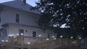 A wooden bridge with railings and lights, leading to a white building with a chimney. - Pappys place at Smoke Hole (Upper Tract)