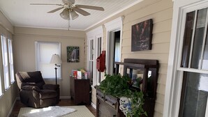 A spacious living room with a ceiling fan, a large window, a dark wooden cabinet, and a patterned rug. - Pappys place at Smoke Hole (Upper Tract)