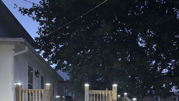 A wooden deck with a ramp leading to a house entrance, surrounded by grass and trees. - Pappys place at Smoke Hole (Upper Tract)