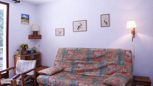 En hyggelig stue med en stribet sofa, et træsidebord med en lampe og indrammet kunst på væggen.