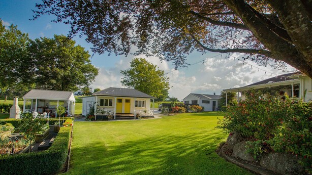 A well-maintained lawn with a gazebo, a yellow house, and a white house with a porch.