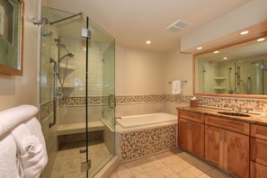 A modern bathroom with a glass-enclosed shower, a freestanding bathtub, wooden cabinets, and a large mirror.