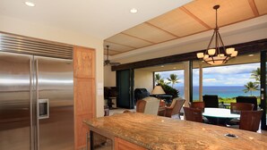 A modern kitchen with a stainless steel refrigerator, wooden cabinets, and a granite countertop.