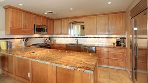 A modern kitchen with wooden cabinets, stainless steel appliances, and a granite countertop.