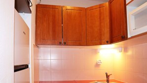 Una cocina compacta con armarios de madera, un lavamanos de acero inoxidable y un horno empotrado.