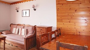 Una habitación acogedora con una mesa de comedor de madera, un sofá con cojines estampados y una pared de madera.