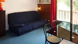 A room with a dark blue sofa, a glass table with a chair, a lamp, and a painting on the wall. - Comfortable Studio 4 Pers, Near Station and Chairlift, Les Orres (Les Orres)