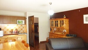 Un espace de vie compact comprenant une table à manger, un canapé et un coin cuisine avec des meubles en bois et un dosseret carrelé.
