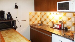 Une cuisine compacte équipée d’un four à micro-ondes, d’une machine à café et d’un petit réfrigérateur.