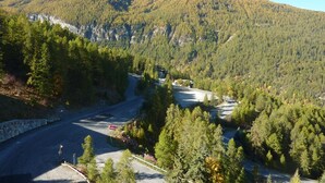 A mountainous landscape with a winding road, dense forest, and a clear sky. - Cozy studio 5 pers, direct slope access, southwest balcony (Les Orres)
