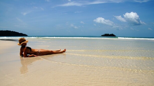 A person lying on a sandy beach with clear blue water and a distant island. - Green Ocean Koh Rong (Koh Rong)