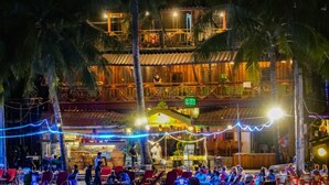 A multi-story building with outdoor seating areas, palm trees, and string lights. - Green Ocean Koh Rong (Koh Rong)