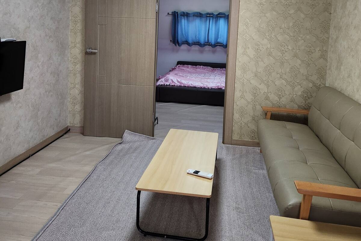 Una habitación funcional con cama, sofá, televisión y escritorio.