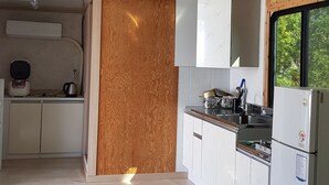 Una cocina moderna con armarios blancos, un muro decorativo de madera, una estufa empotrada y un refrigerador.