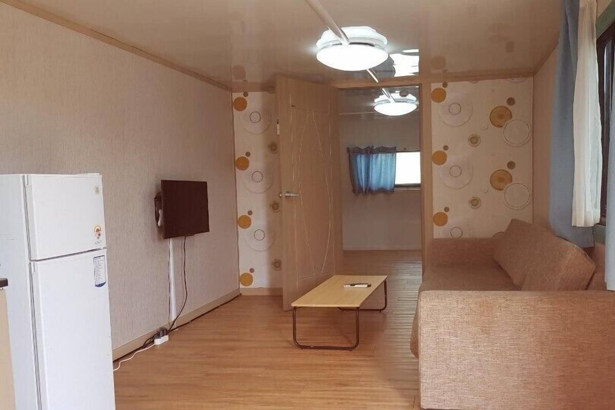 Un espacio habitable compacto con kitchenette, televisor de pantalla plana, sofá y mesa de comedor.
