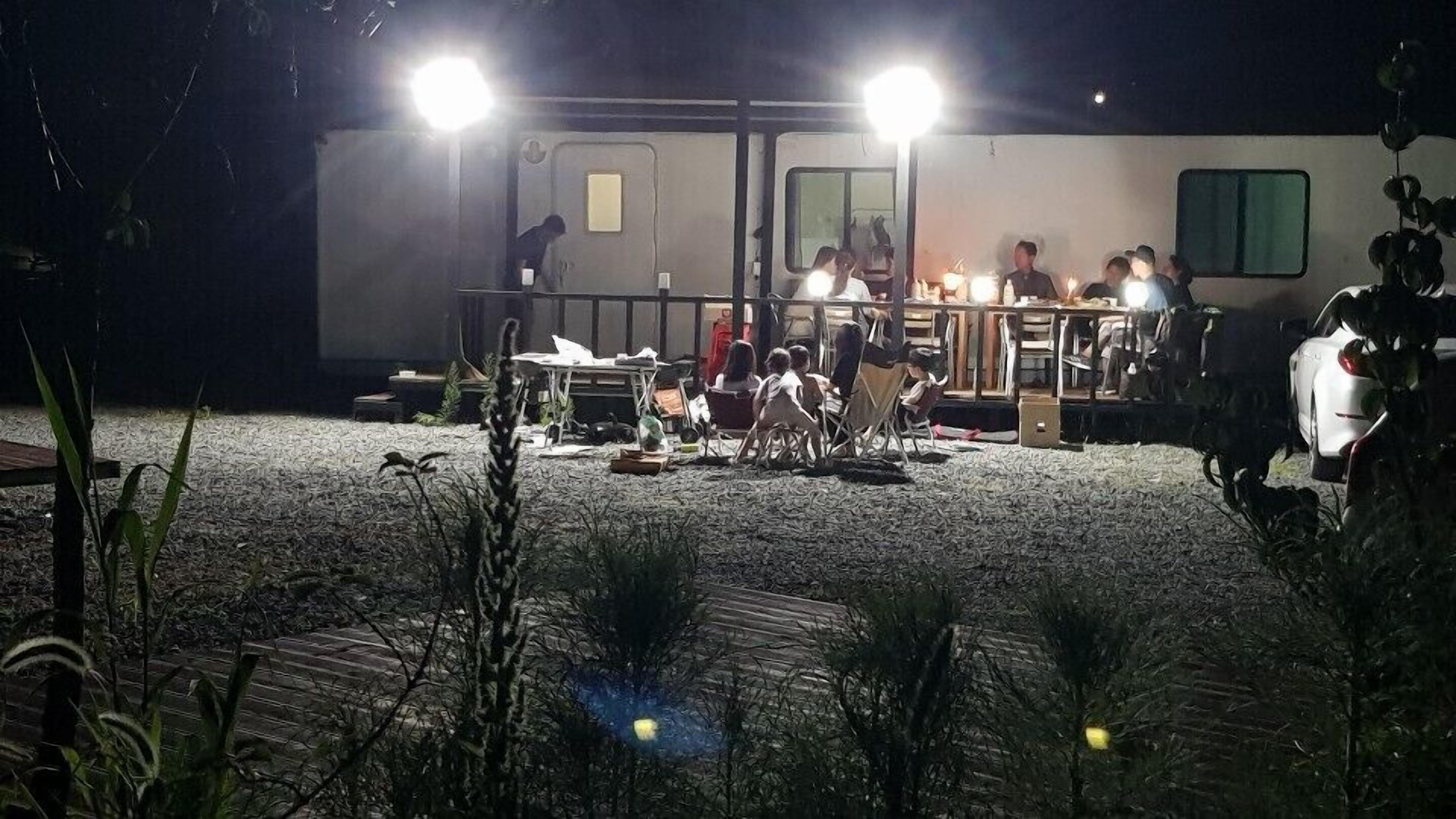 A stationary caravan with a covered dining area, surrounded by gravel and sparse vegetation.