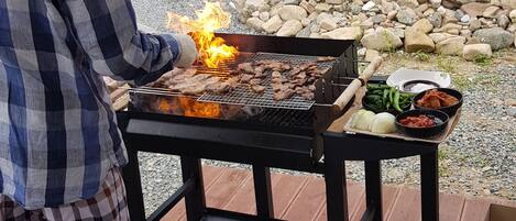 A man grilling meat on an outdoor barbecue.