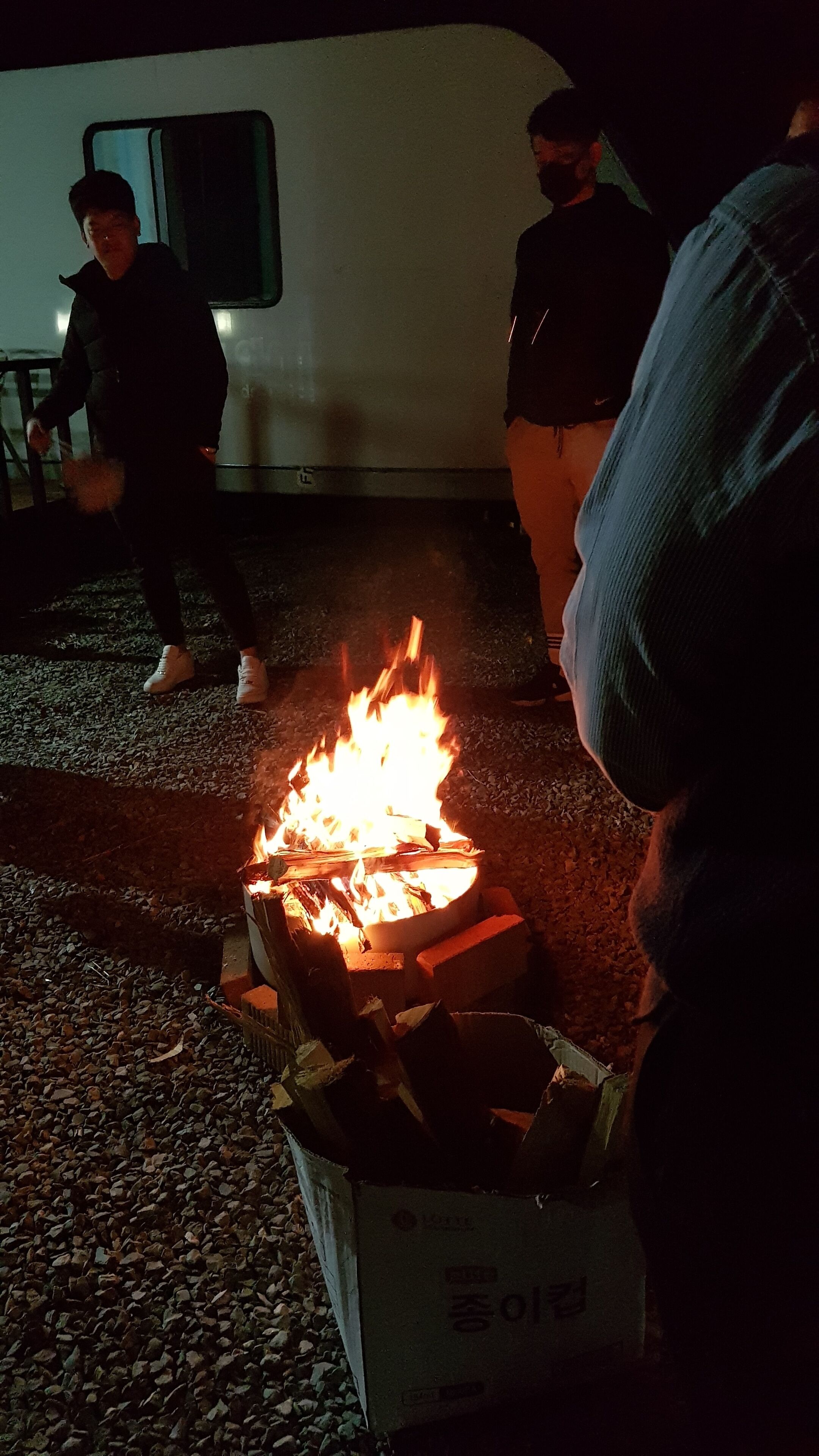A campfire with logs and a box labeled 'Chung' in the foreground.