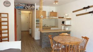 A compact kitchen with a central island, wooden chairs, and a dining table. - Renovated studio, ski-in/ski-out, south-facing balcony (Les Orres)