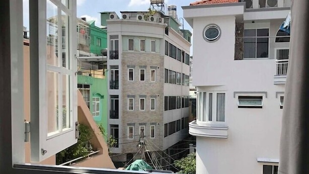 A view of a multi-story building with a mix of architectural styles, including a corner building with a unique design and a building with a red-tiled roof. - Saigon House 18Bis (Ho Chi Minh City)