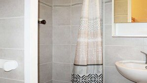 Et badeværelse med bruseforhæng, vask og toilet.