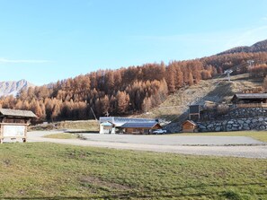 A mountain lodge with a ski lift, surrounded by autumn trees and a clear sky.