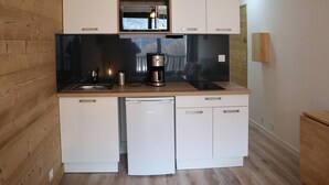 A compact kitchen with white cabinets, a coffee maker, and a sink. - Newly Renovated Studio for 2 in Central Location with Direct Slope Access, Balcony & Stunning Views (Les Orres)