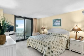 Relax in this serene hotel room featuring a large bed, a potted plant, and a stunning ocean view.