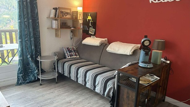 A cozy room with a sofa, a small table, a lamp, and a clock on the wall. - Lovely studio for 4, ski-in/ski-out, wifi, pets allowed (Les Orres)