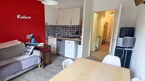 A compact living space with a kitchenette, a dining area, and a red accent wall. - Lovely studio for 4, ski-in/ski-out, wifi, pets allowed (Les Orres)