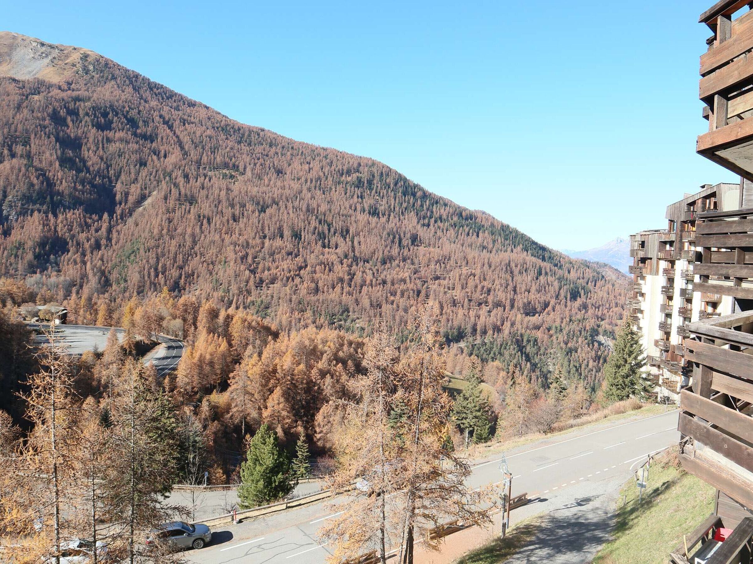 A mountain landscape with a road and a building with balconies.