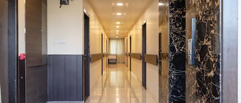 A hotel corridor with a marble wall, wooden paneling, and a ceiling with recessed lighting.