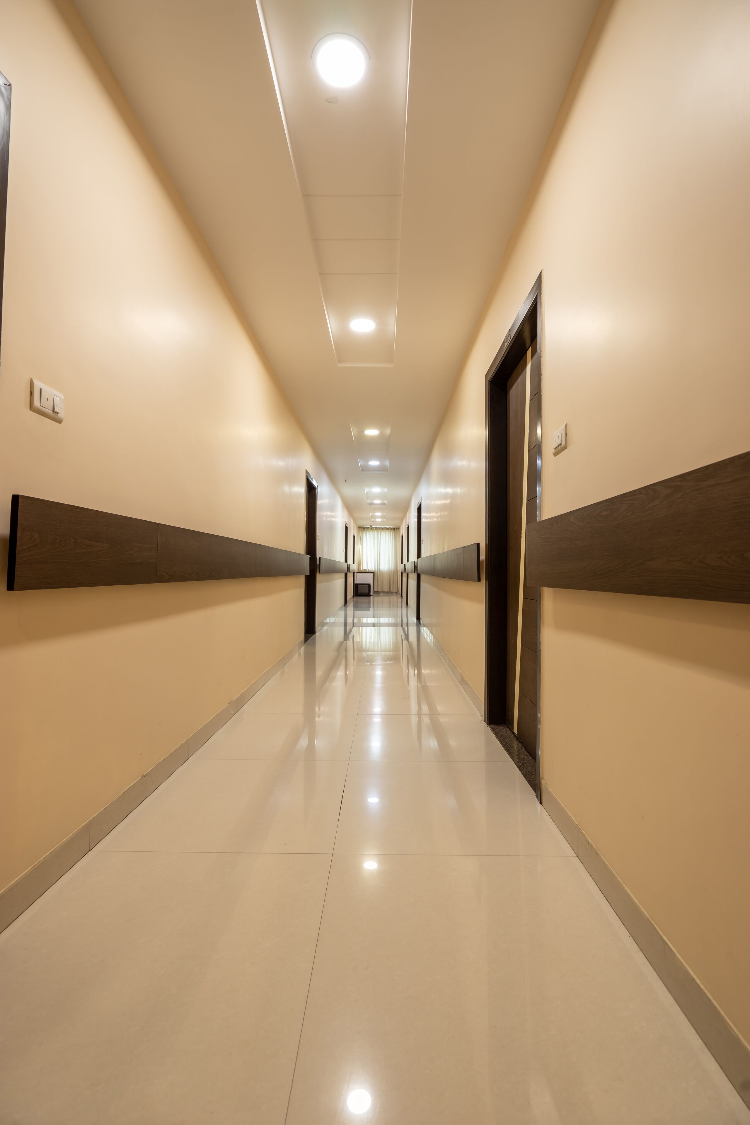 A long, well-lit hallway with a reflective floor, leading to a door at the end.
