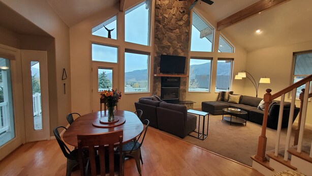 Un amplio salón con chimenea de piedra, ventanas grandes y una zona de estar acogedora.