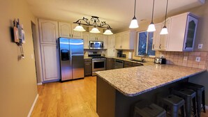 Una cocina moderna con electrodomésticos de acero inoxidable, encimera de granito e iluminación colgante.