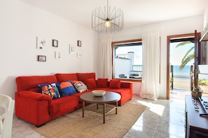 Un canapé rouge agrémenté de coussins colorés, une table ronde et un luminaire moderne.