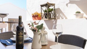 Una mesa con una botella de vino, una jarrón con flores, una copa y un farol.