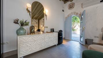 A room with a white cabinet, a mirror, a vase, and a door leading outside.