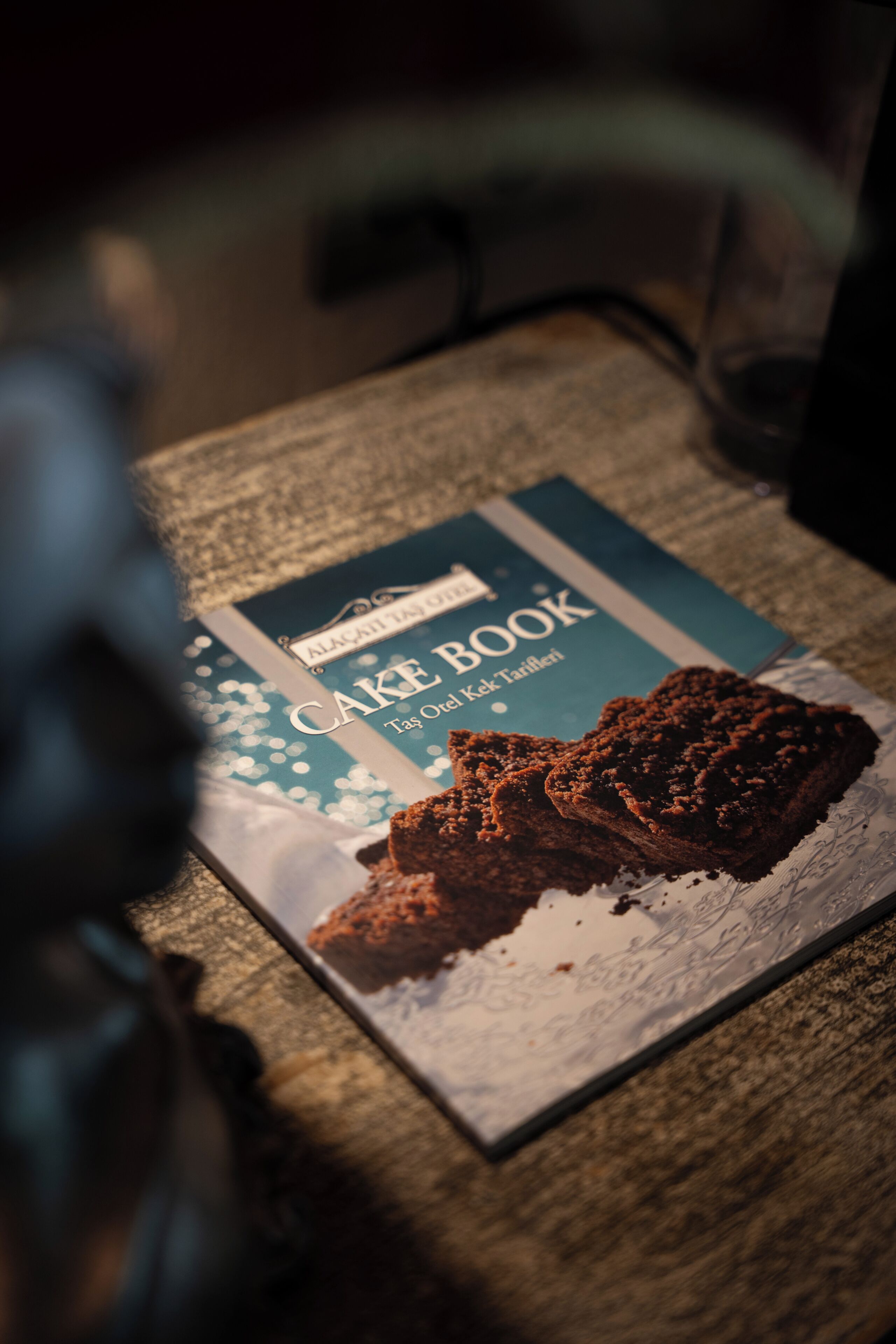 A book titled 'Cake Book' with a picture of a cake on its cover, placed on a table.