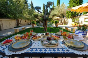 Un área de comedor al aire libre con una mesa preparada para una comida, rodeada de follaje y árboles.