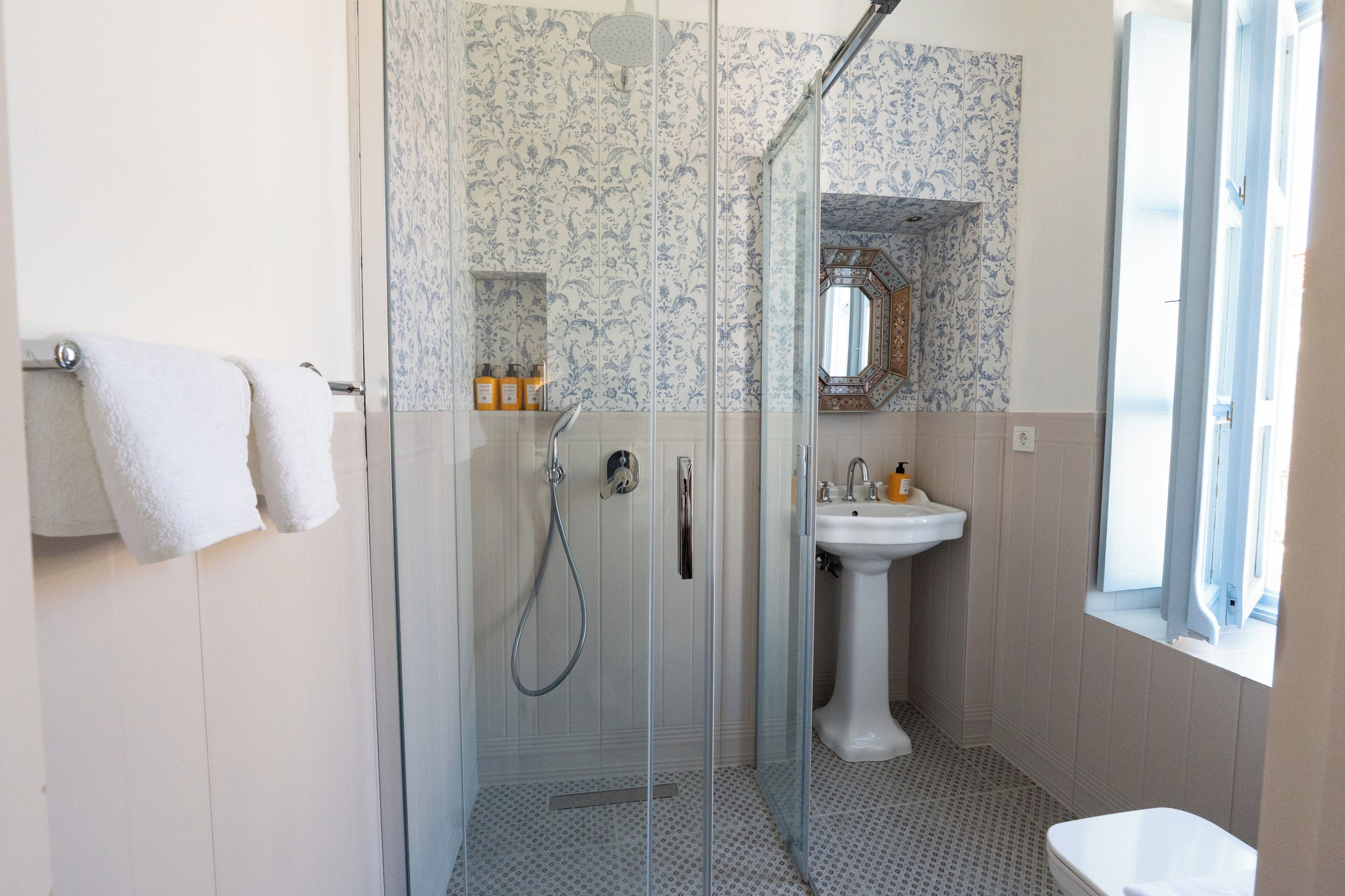 Een badkamer met een douchecabine, een wastafel op een zuil en een wit toilet.