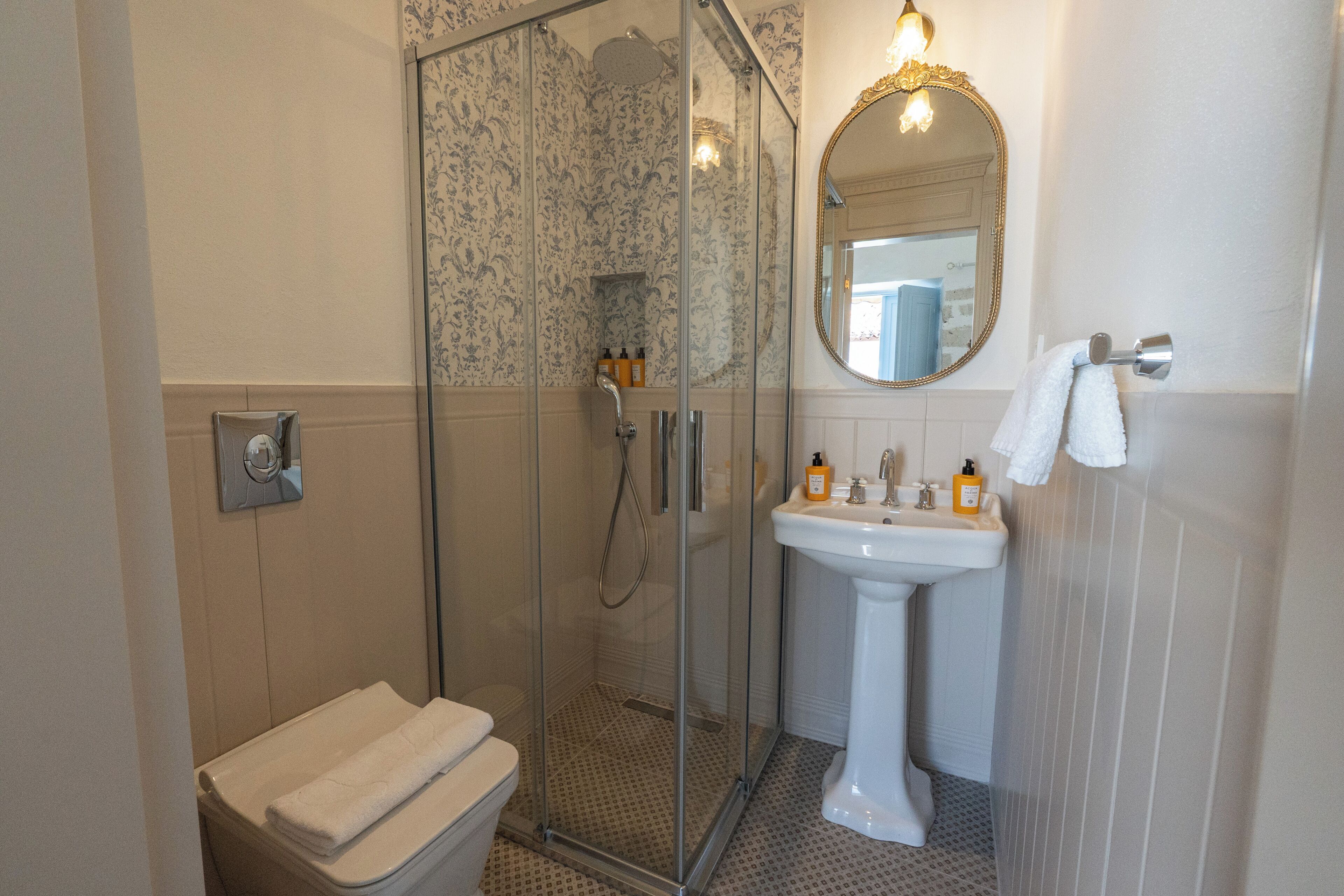 A bathroom with a glass-enclosed shower, a white sink, and a toilet.