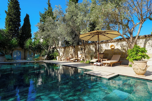 Una piscina al aire libre, sombrillas, sillones reclinables de piscina
