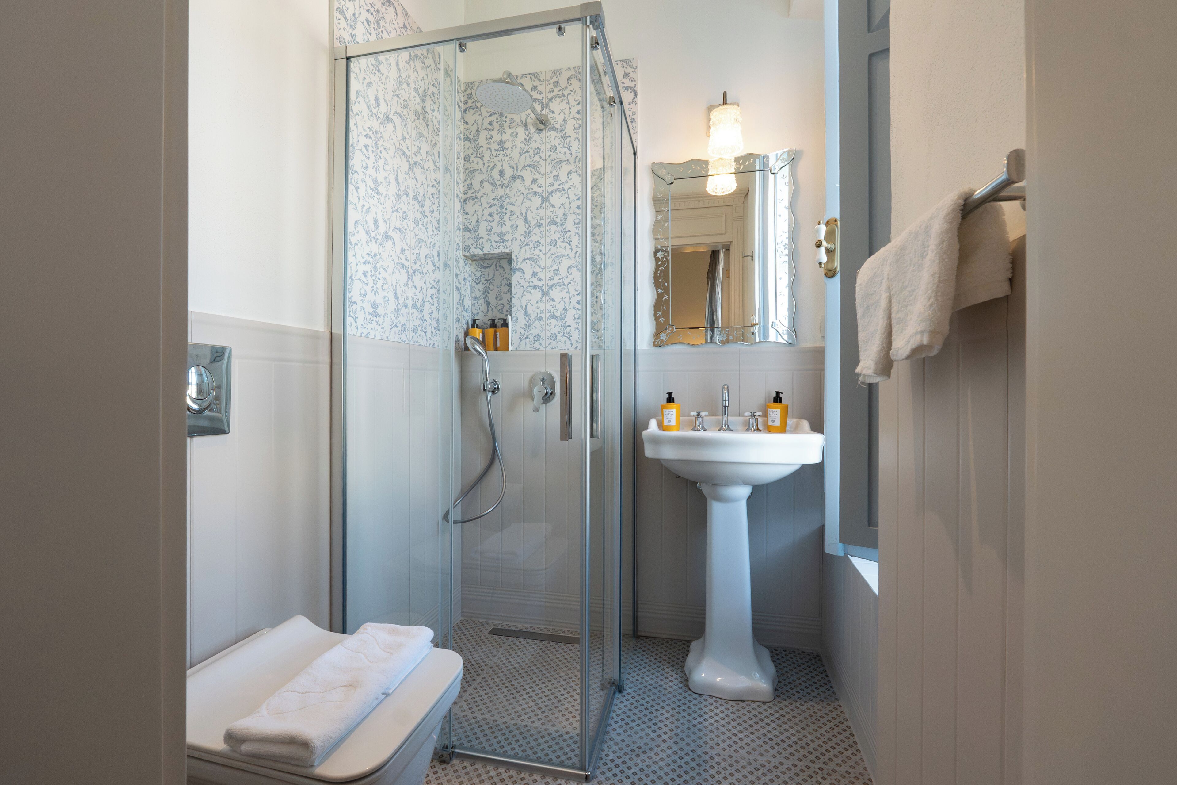 Une salle de bain avec une douche à parois de verre, un lavabo sur colonne et des toilettes.