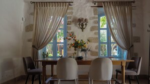 A dining area with a wooden table, four chairs, and a vase of flowers. - Tas Otel (Cesme)