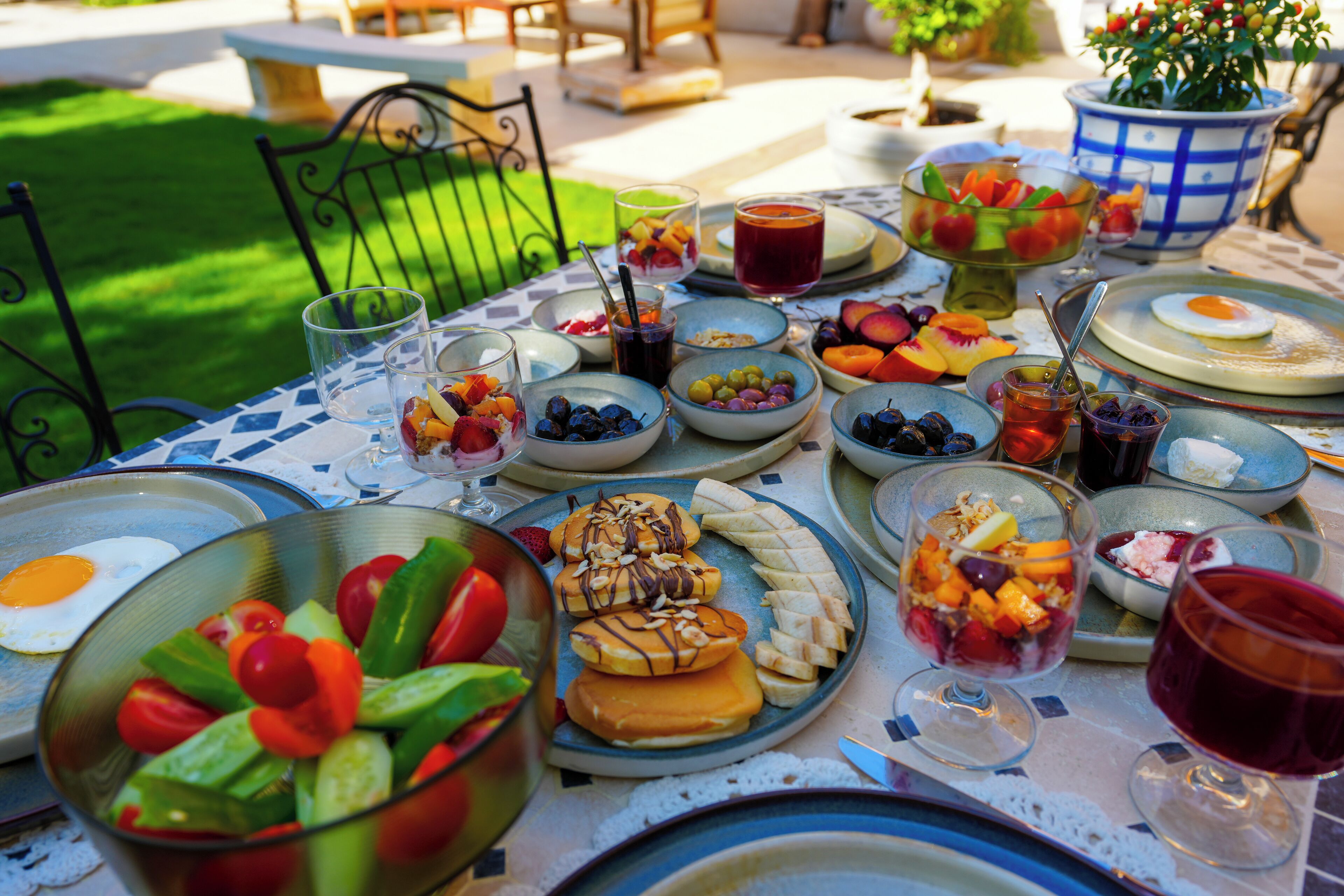 A table set with various dishes, including fruits, vegetables, and a glass of red wine, suggesting a meal or gathering.