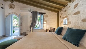 A bedroom with a large bed, a window with curtains, a chair, and a lamp. - Tas Otel (Cesme)
