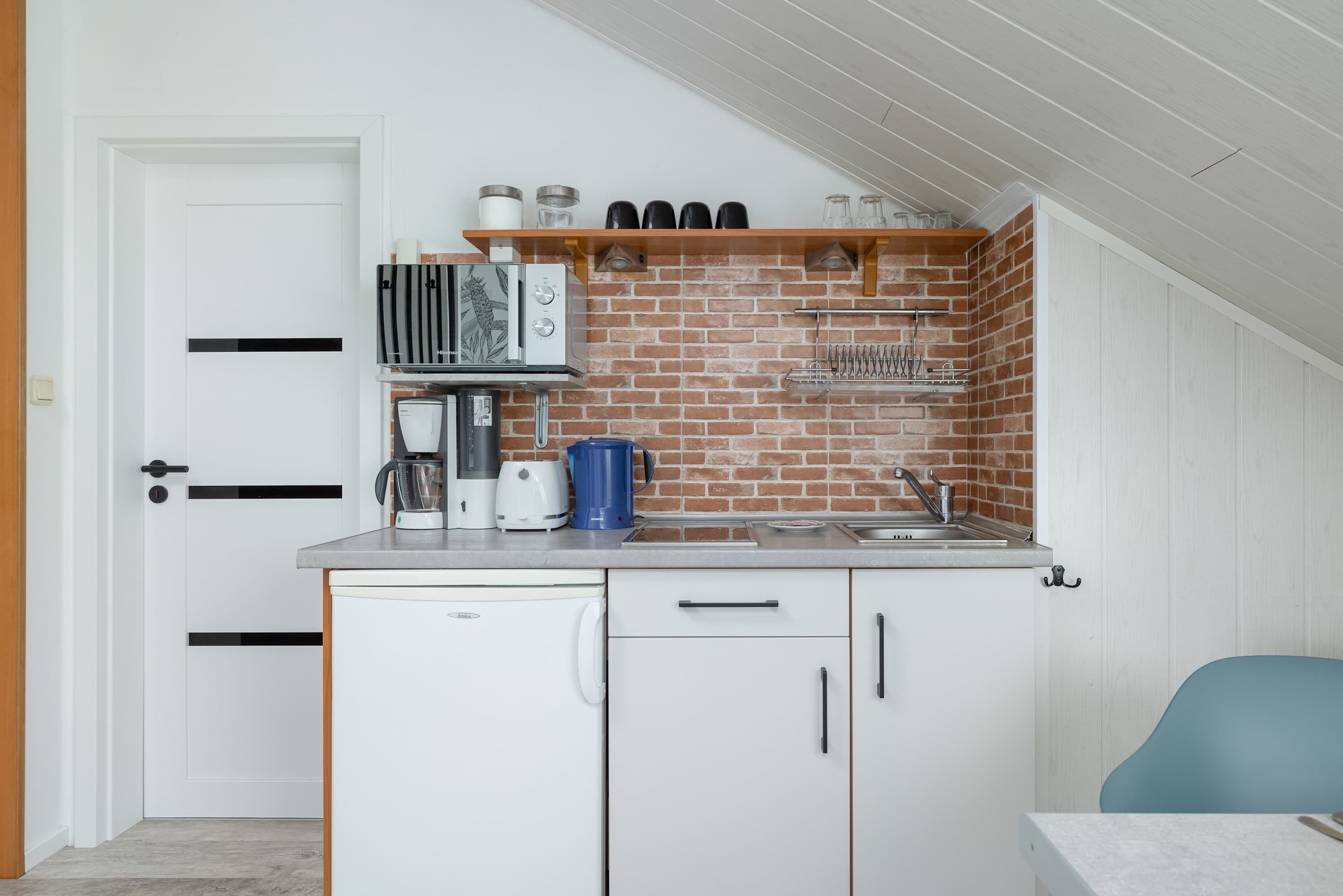 Eine kleine Küche mit Geschirrspüler, Kaffeemaschine, Toaster und Wasserkocher auf der Arbeitsfläche.
