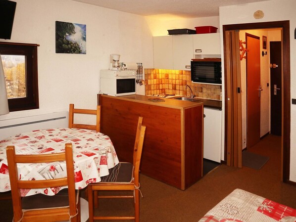 A compact kitchen with a dining area, featuring a small island, basic appliances, and a view of the outside.