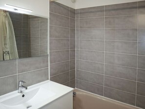 A bathroom with a white sink, a mirror, and grey tiled walls. - Ski-In/Out Studio with Southern Balcony, Stunning Valley and Skating Rink Views, Sleeps 4 (Les Orres)
